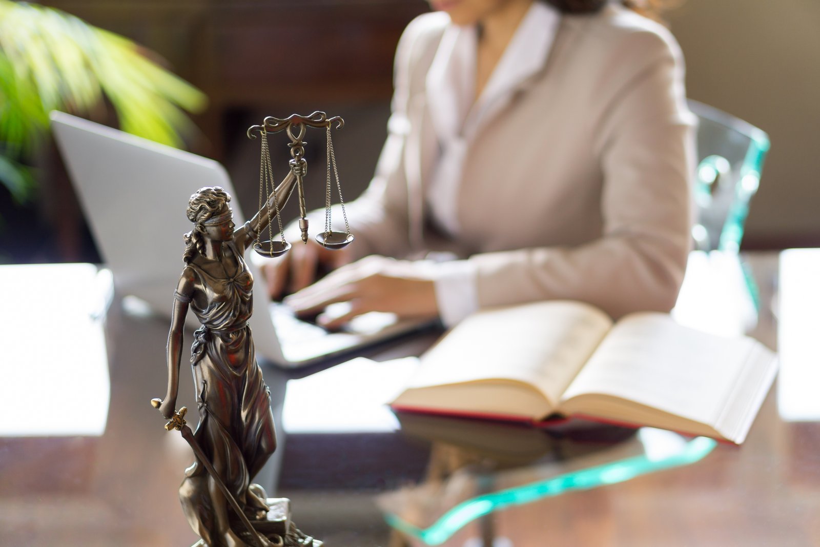 Statue of Justice and lawyer working on a laptop